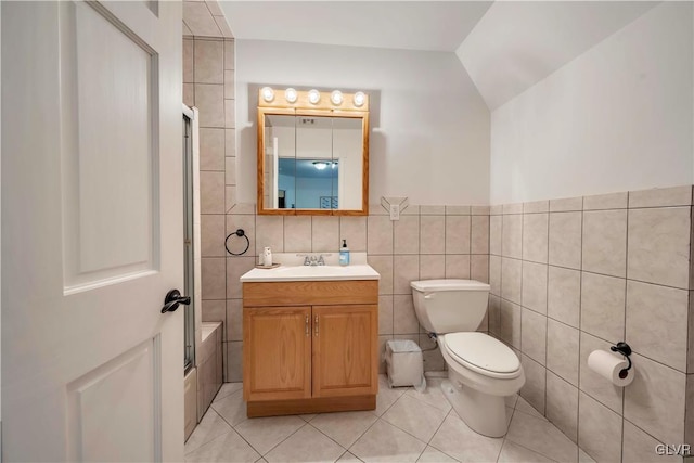 full bathroom featuring vanity, tile patterned floors, lofted ceiling, tile walls, and toilet