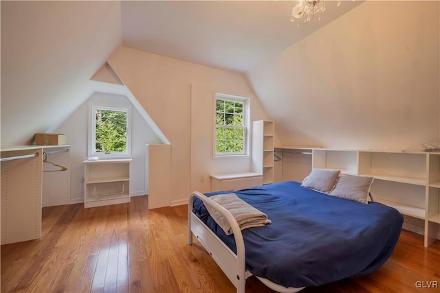 bedroom with light wood-type flooring, vaulted ceiling, and multiple windows