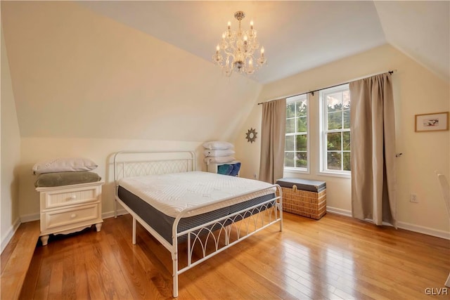 bedroom featuring light hardwood / wood-style flooring, lofted ceiling, and a chandelier