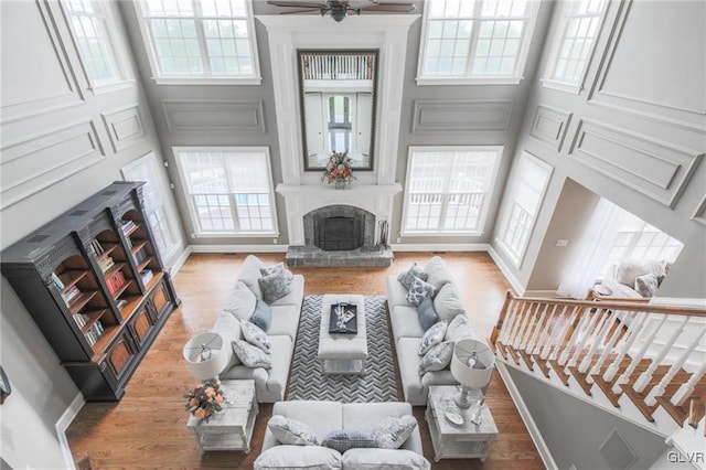 living room with light wood-type flooring, a healthy amount of sunlight, a high ceiling, and ceiling fan