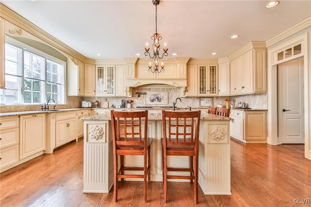 kitchen featuring a center island with sink, pendant lighting, an inviting chandelier, and light hardwood / wood-style floors