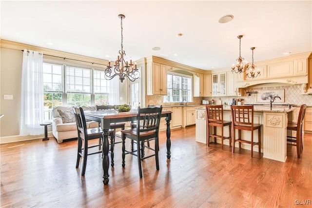 dining area with ornamental molding, sink, a chandelier, and light hardwood / wood-style floors