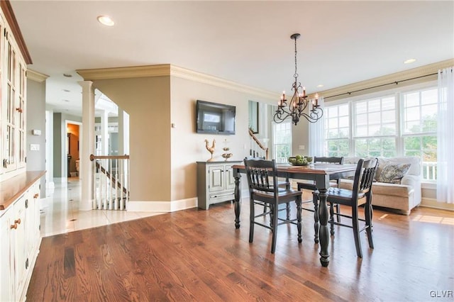 dining area with crown molding, hardwood / wood-style floors, a chandelier, and decorative columns