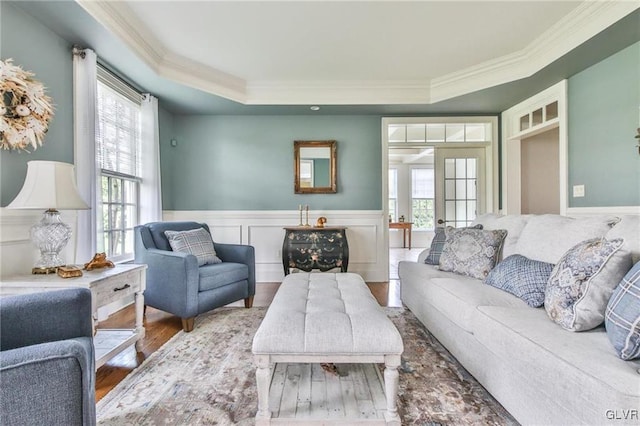 living room with hardwood / wood-style flooring, a raised ceiling, crown molding, and french doors