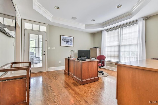 home office featuring crown molding, plenty of natural light, a raised ceiling, and light hardwood / wood-style floors