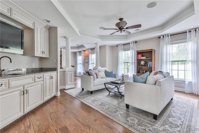 living room with a wealth of natural light, ceiling fan, sink, and decorative columns