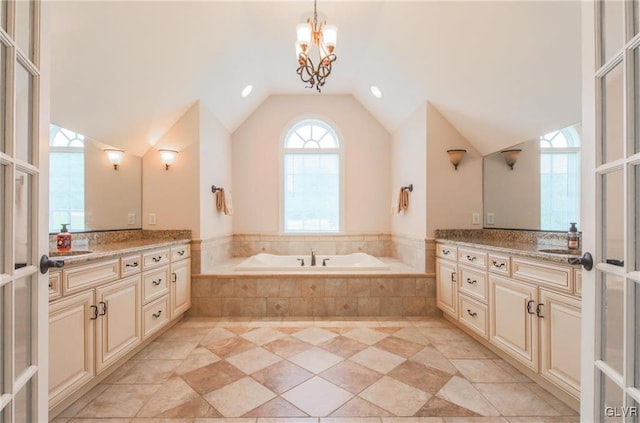 bathroom featuring lofted ceiling, vanity, an inviting chandelier, and a relaxing tiled tub