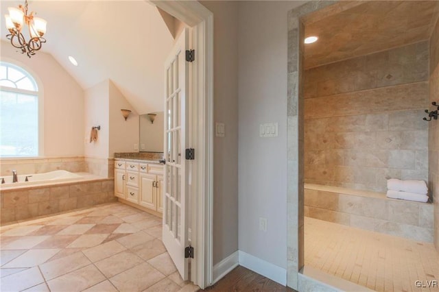 bathroom with tile patterned flooring, an inviting chandelier, vaulted ceiling, shower with separate bathtub, and vanity