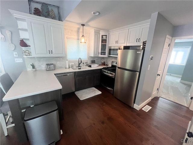 kitchen featuring stainless steel appliances, white cabinetry, plenty of natural light, and decorative light fixtures