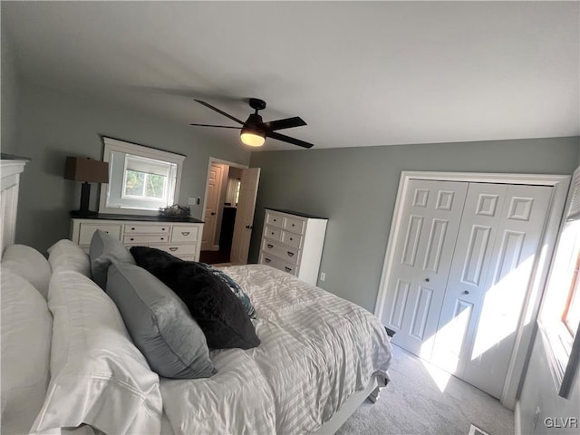 carpeted bedroom with ceiling fan, a closet, and vaulted ceiling