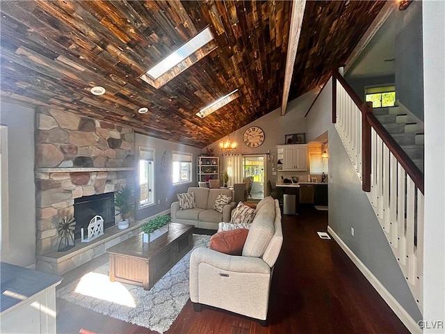 living room with high vaulted ceiling, a stone fireplace, dark hardwood / wood-style flooring, beam ceiling, and a skylight