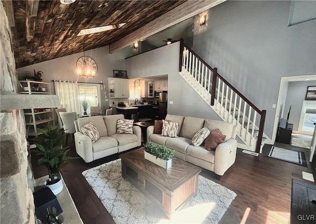 living room featuring a skylight, beamed ceiling, dark wood-type flooring, and a wealth of natural light