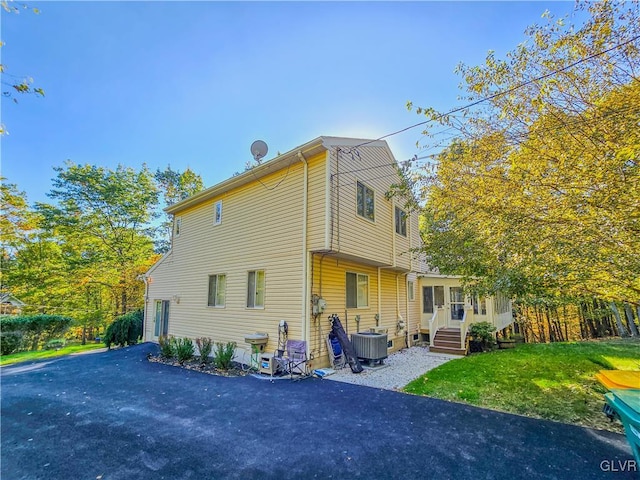 rear view of property with a lawn and central AC unit