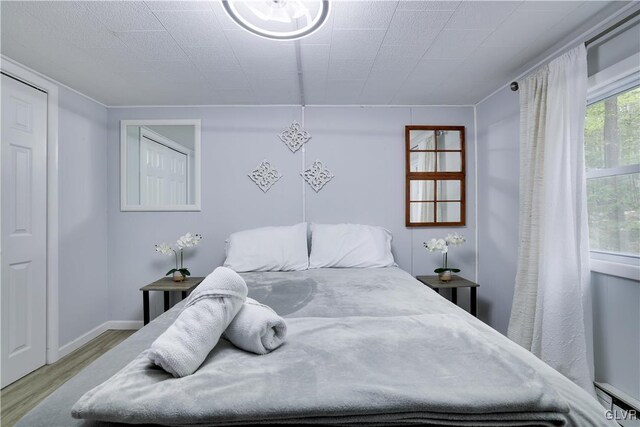 bedroom featuring light wood-type flooring and a baseboard heating unit