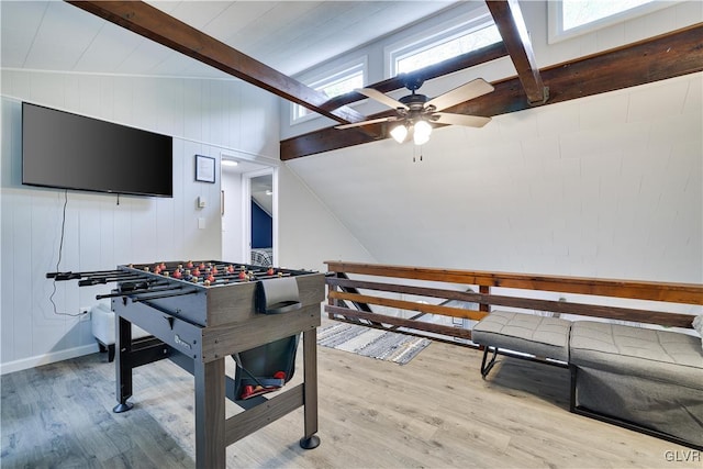 playroom with ceiling fan, plenty of natural light, wood-type flooring, and vaulted ceiling with beams