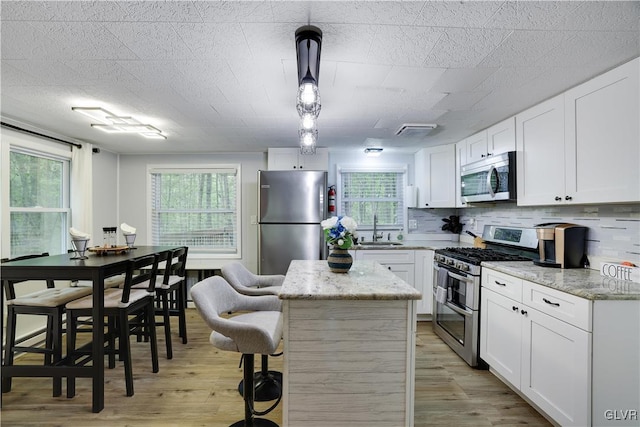 kitchen featuring a healthy amount of sunlight, sink, a center island, and appliances with stainless steel finishes