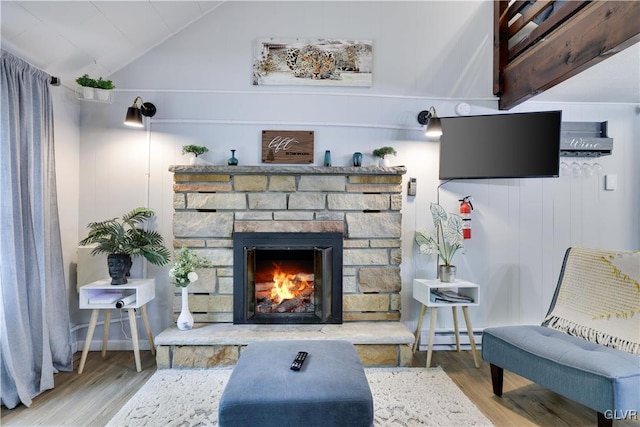 living room featuring lofted ceiling, a baseboard radiator, a stone fireplace, and hardwood / wood-style flooring