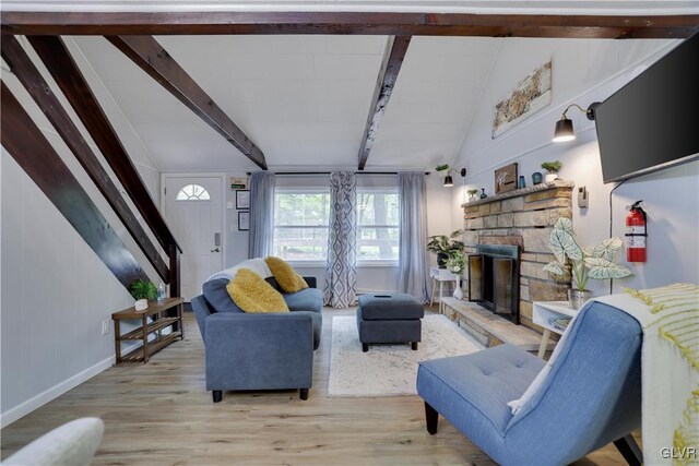 living room with hardwood / wood-style flooring, vaulted ceiling with beams, and a stone fireplace