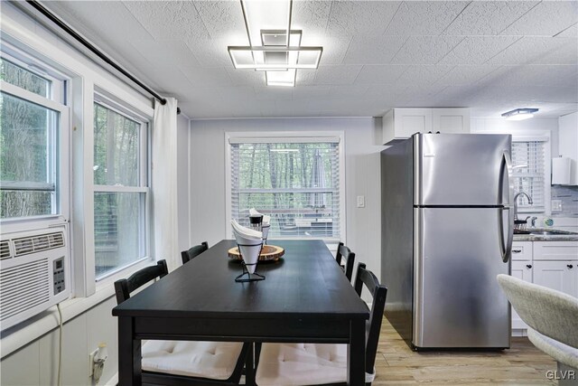 dining room featuring cooling unit, light hardwood / wood-style flooring, and sink