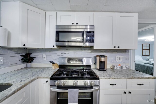 kitchen featuring appliances with stainless steel finishes, light stone countertops, and white cabinets