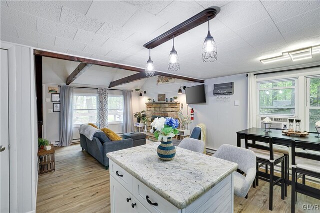 kitchen with hanging light fixtures, a wealth of natural light, a fireplace, and white cabinetry