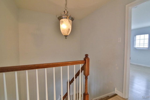 stairs featuring wood-type flooring and a notable chandelier