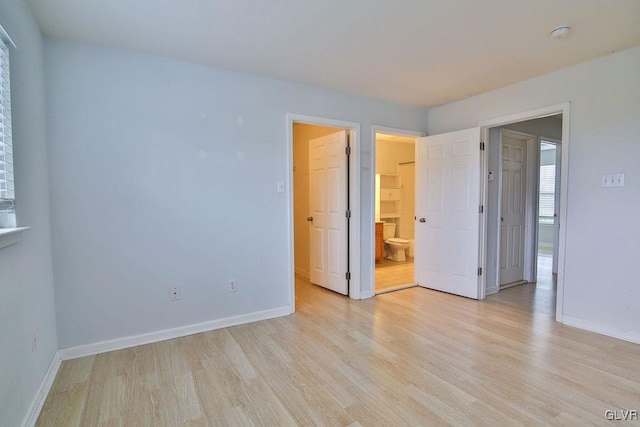 unfurnished bedroom with light hardwood / wood-style floors and ensuite bath