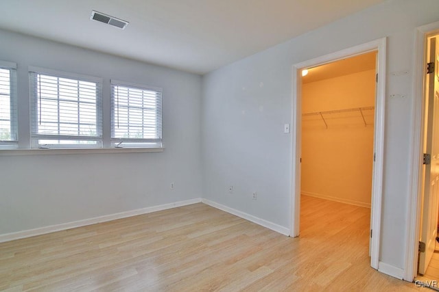 unfurnished bedroom featuring light hardwood / wood-style flooring, a closet, and a walk in closet