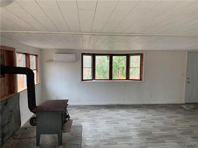 unfurnished room featuring plenty of natural light, light hardwood / wood-style flooring, an AC wall unit, and a wood stove