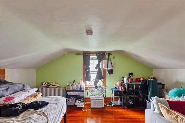 bedroom featuring wood-type flooring, radiator heating unit, and vaulted ceiling