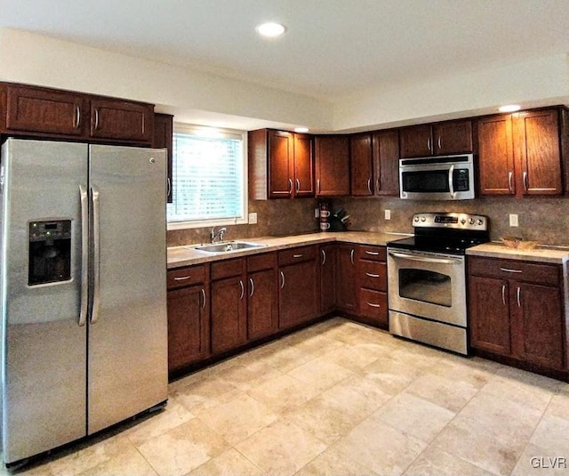 kitchen with dark brown cabinetry, backsplash, appliances with stainless steel finishes, and sink