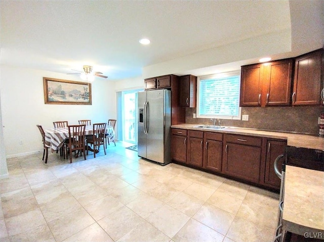 kitchen with decorative backsplash, stainless steel refrigerator with ice dispenser, sink, dark brown cabinetry, and ceiling fan