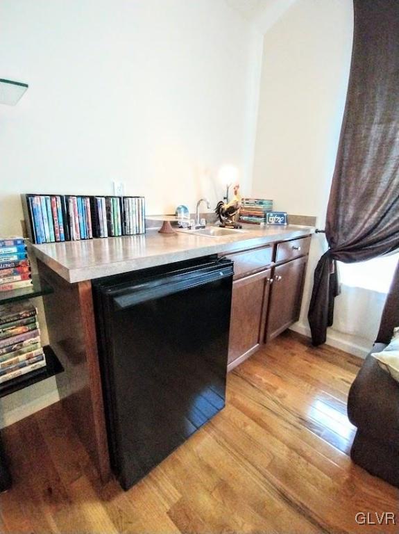 interior space with light hardwood / wood-style flooring, dishwasher, dark brown cabinetry, and sink