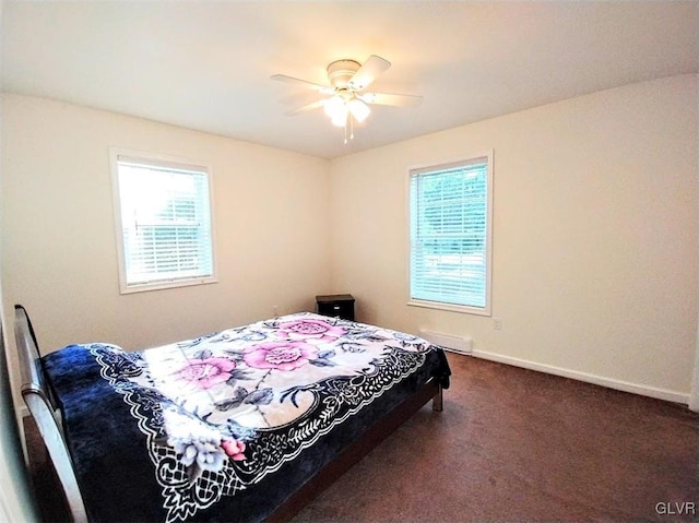 bedroom with ceiling fan, multiple windows, and dark colored carpet