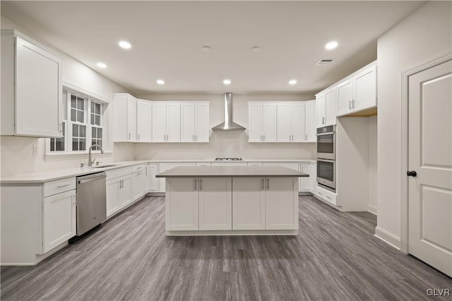 kitchen with appliances with stainless steel finishes, dark hardwood / wood-style floors, wall chimney exhaust hood, and white cabinetry