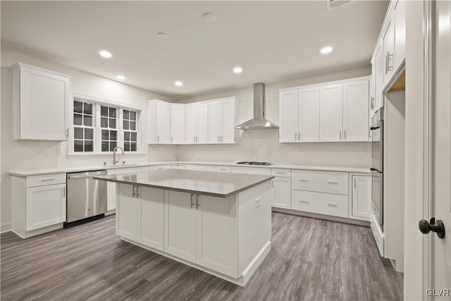 kitchen featuring white cabinetry, dark hardwood / wood-style floors, wall chimney exhaust hood, a kitchen island, and stainless steel dishwasher