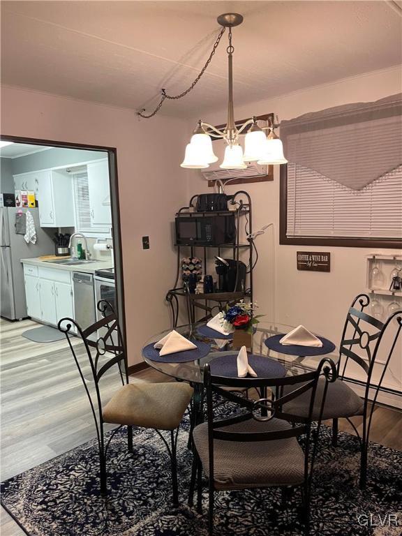 dining space with wood-type flooring, sink, and a notable chandelier