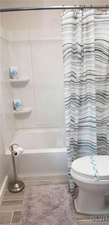 bathroom featuring toilet, shower / bath combination with curtain, and hardwood / wood-style floors