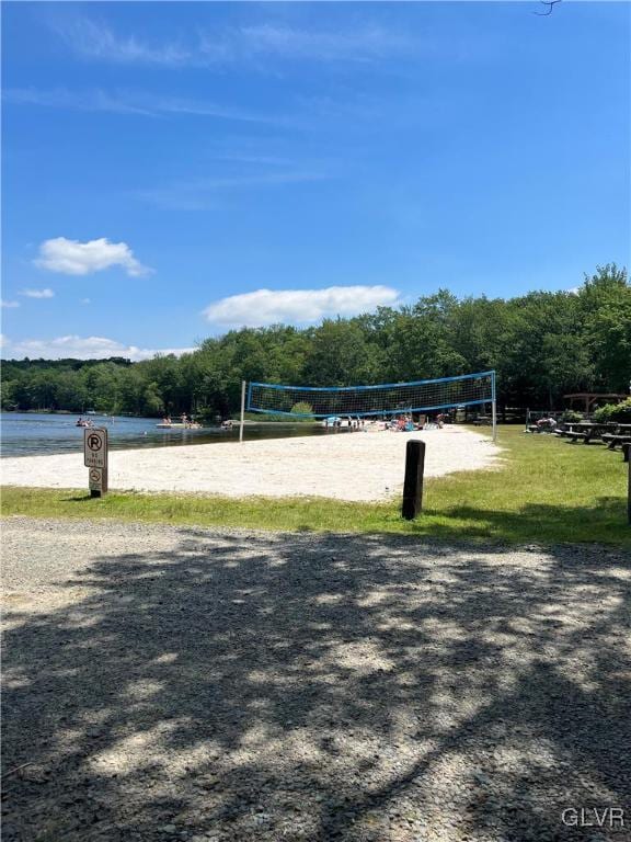 view of property's community with volleyball court and a water view