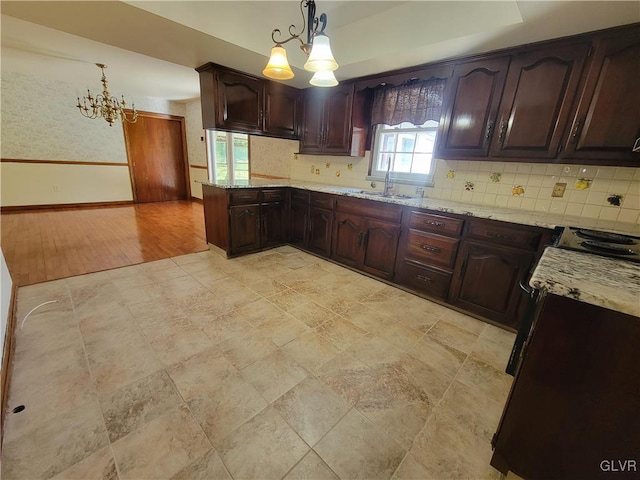 kitchen featuring light hardwood / wood-style flooring, a chandelier, decorative light fixtures, and light stone countertops