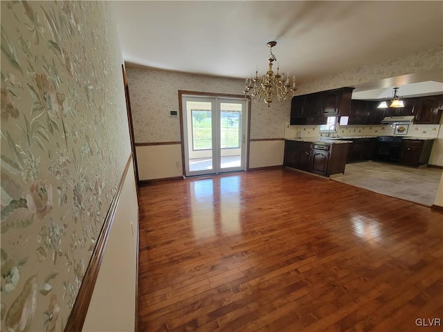 kitchen featuring dark brown cabinetry, light hardwood / wood-style flooring, an inviting chandelier, and hanging light fixtures