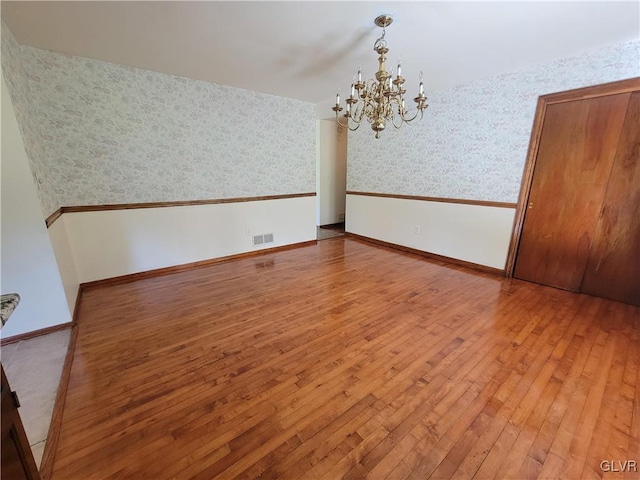 spare room featuring hardwood / wood-style floors and an inviting chandelier