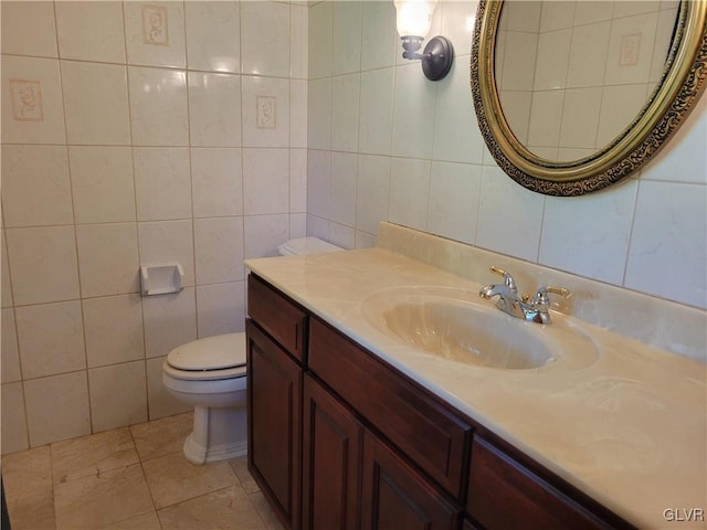 bathroom with vanity, toilet, tile patterned floors, and tile walls