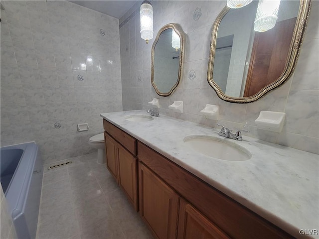 bathroom featuring washer / dryer, tile walls, toilet, vanity, and tile patterned flooring