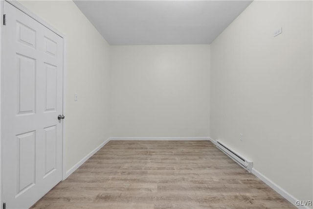 spare room with a baseboard heating unit and light hardwood / wood-style floors