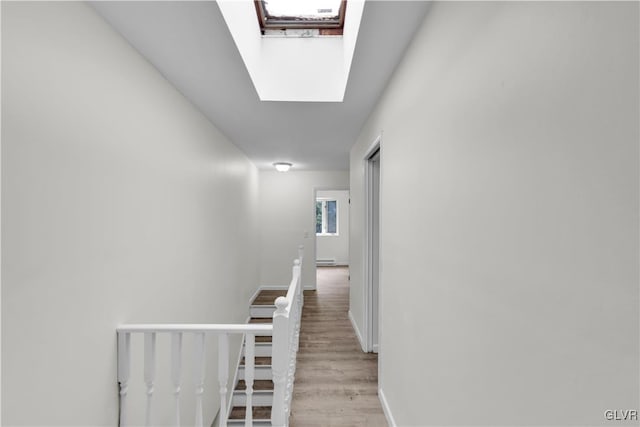 corridor featuring light wood-type flooring and a skylight