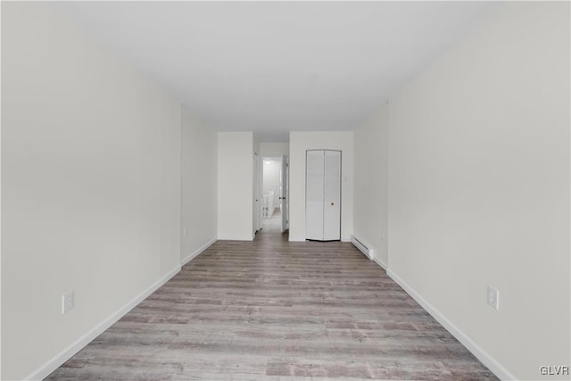 unfurnished room with a baseboard radiator and light wood-type flooring