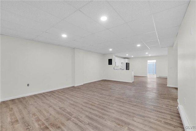 basement featuring stainless steel refrigerator, hardwood / wood-style flooring, and a drop ceiling