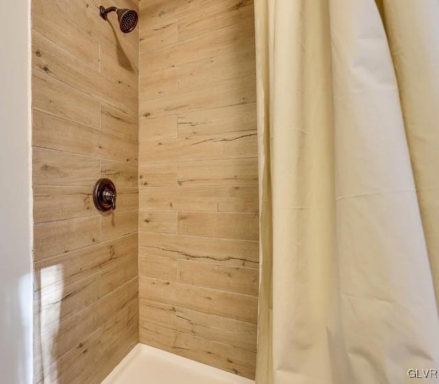 full bath with wooden walls and tiled shower