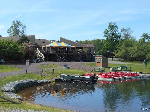 dock area with stairs, a lawn, and a water view